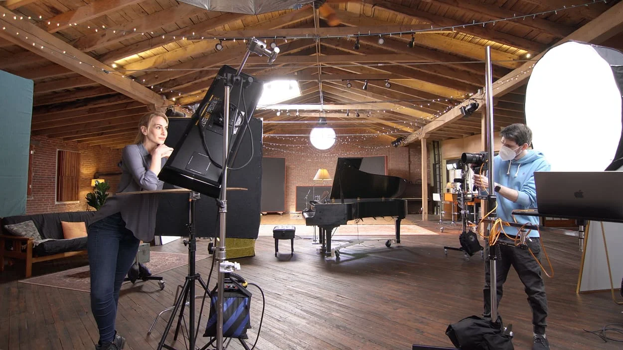 Behind-the-scenes modeling headshot session showing photographer with camera and subject at softbox lighting setup