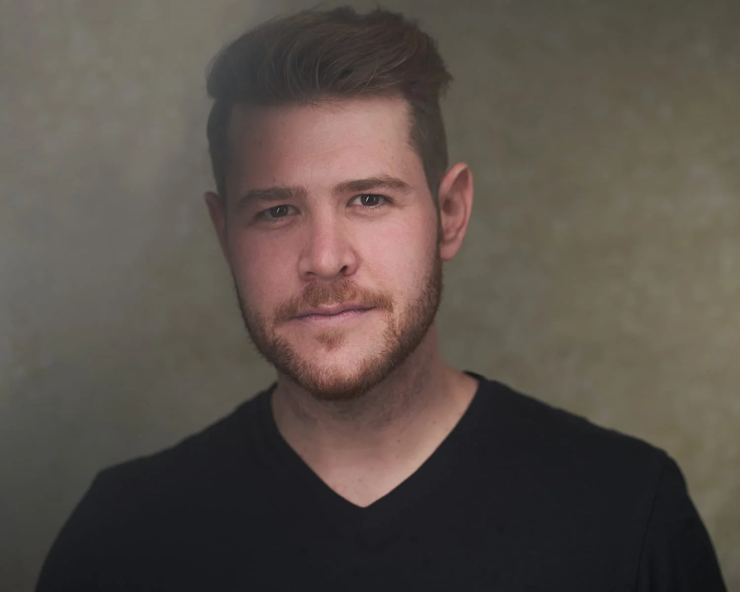 Male actor with neutral expression in black v-neck against studio background — Philadelphia acting headshots