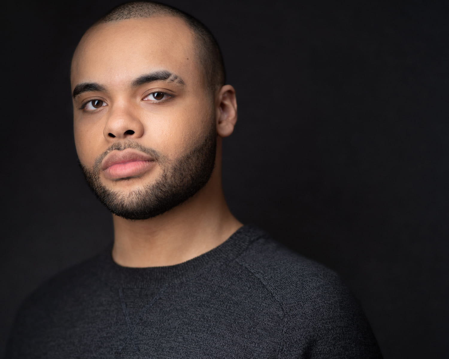 Contemporary studio headshot of young actor in casual black sweater